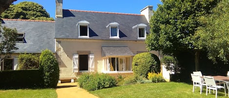 A two-story house with a paved driveway, a covered patio, and a well-maintained lawn.