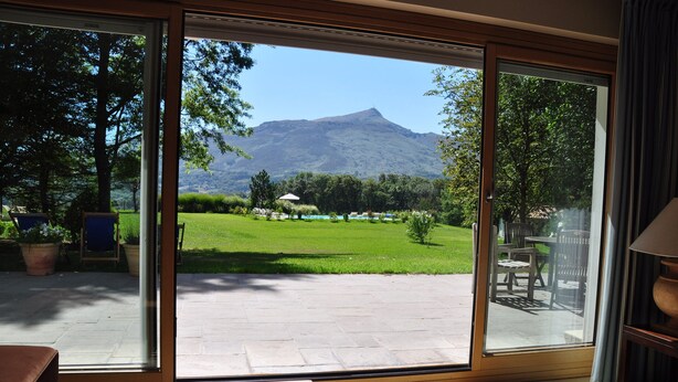 Een kamer met een grote schuifglazen deur die uitkomt op een terras met uitzicht op een berg.