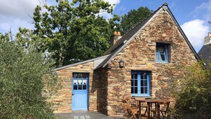A stone house with a blue door and windows, a small outdoor table, and a stone staircase leading to the entrance. - Small charming Breton house (Nivillac)