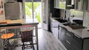 Cocina moderna con una isla grande, un comedor con una silla y vistas al exterior.