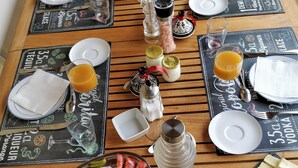 Una mesa de madera dispuesta con platos, vasos y una variedad de alimentos, incluyendo frutas, quesos y carnes.
