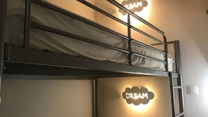 A bunk bed with a 'DREAM' sign above it, a ladder, and a single white pillow.