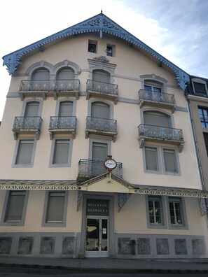 A building with ornate balconies, a sign reading "BELLEVUE," and a door labeled "GEORGES V." - Pied du télécabine. T2 + alcove. Parking couvert. (Cauterets)
