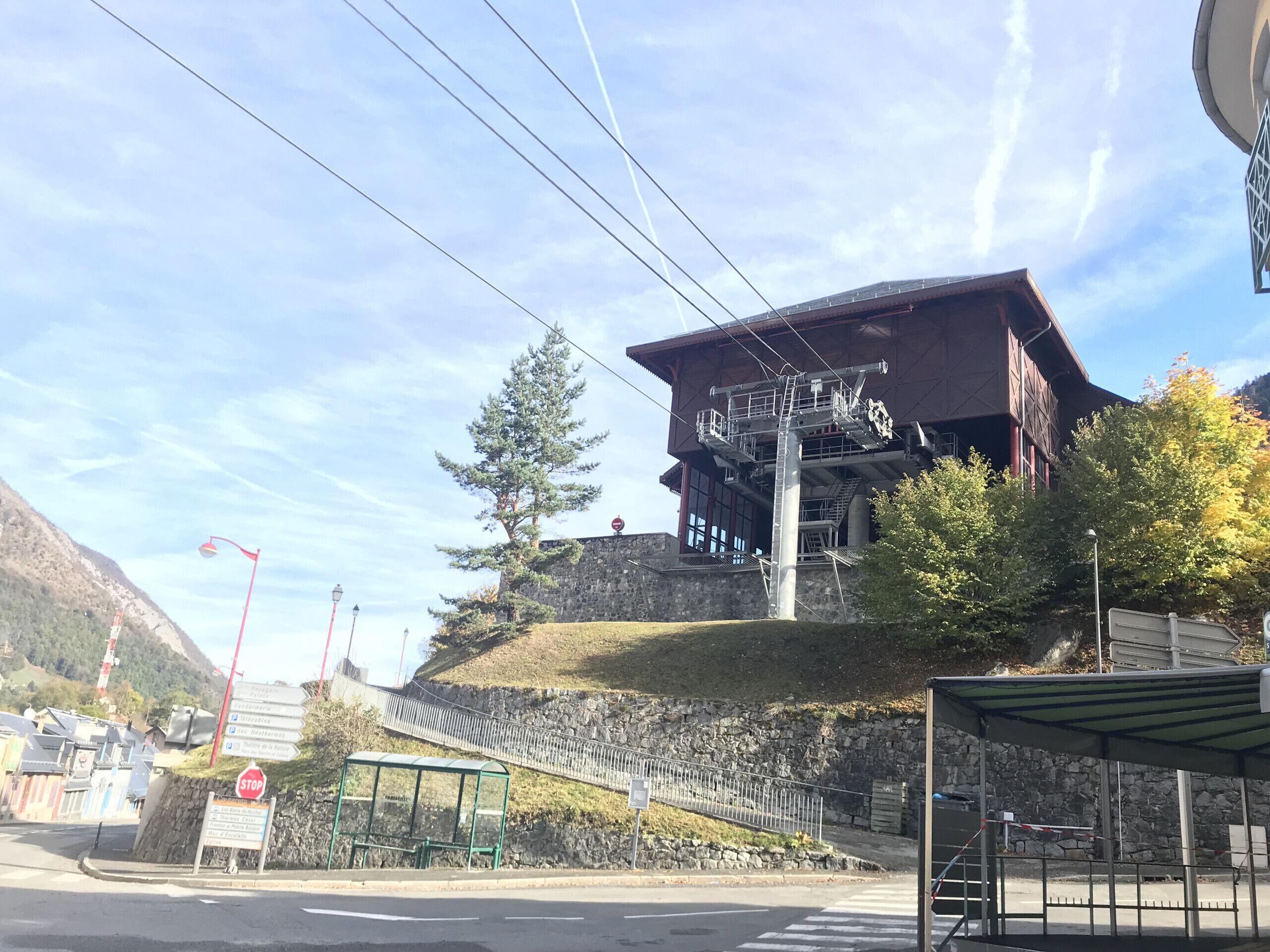A mountain lodge with a ski lift, a stone wall, and a bus stop.