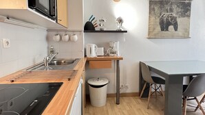 A compact kitchen with a microwave, sink, and wooden countertop.