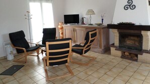 Una sala de estar con chimenea, televisor y comedor con sillas y mesa.