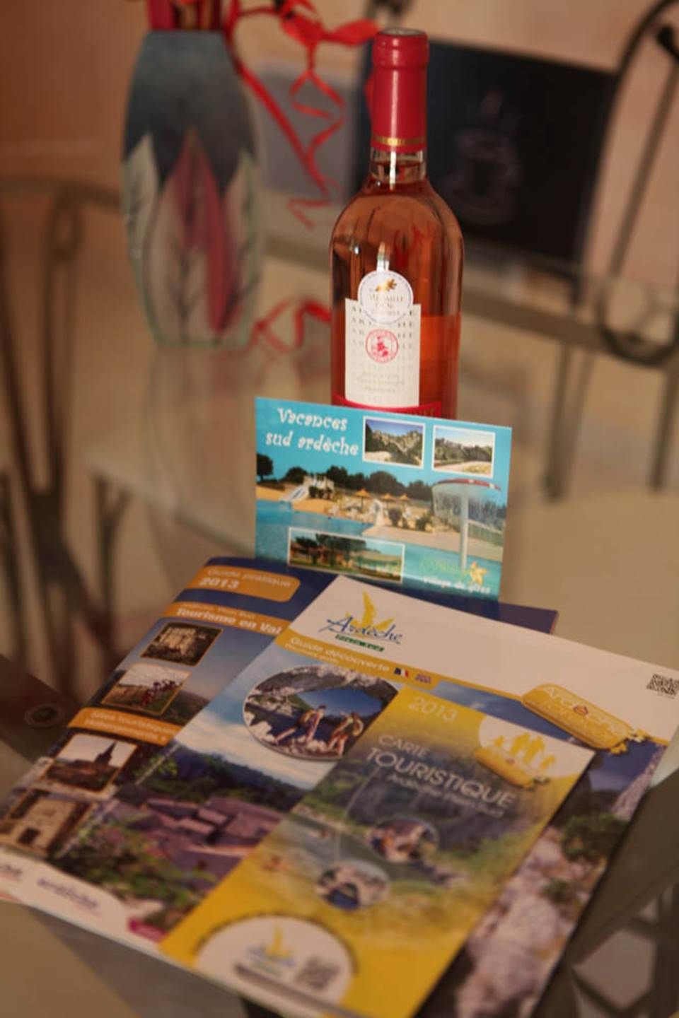 Eine Weinflasche mit Etikett, eine Broschüre mit dem Titel 'Vacances sud ardache' und ein Booklet mit verschiedenen Bildern und Text.
