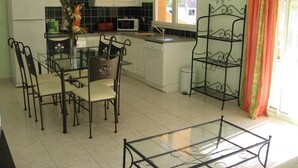 A modern kitchen with white cabinets, a dining table with chairs, a microwave, and a sink.