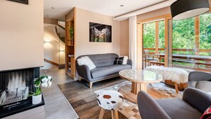 En moderne stue med en grå sofa, et rundt sofabord og en pejs.