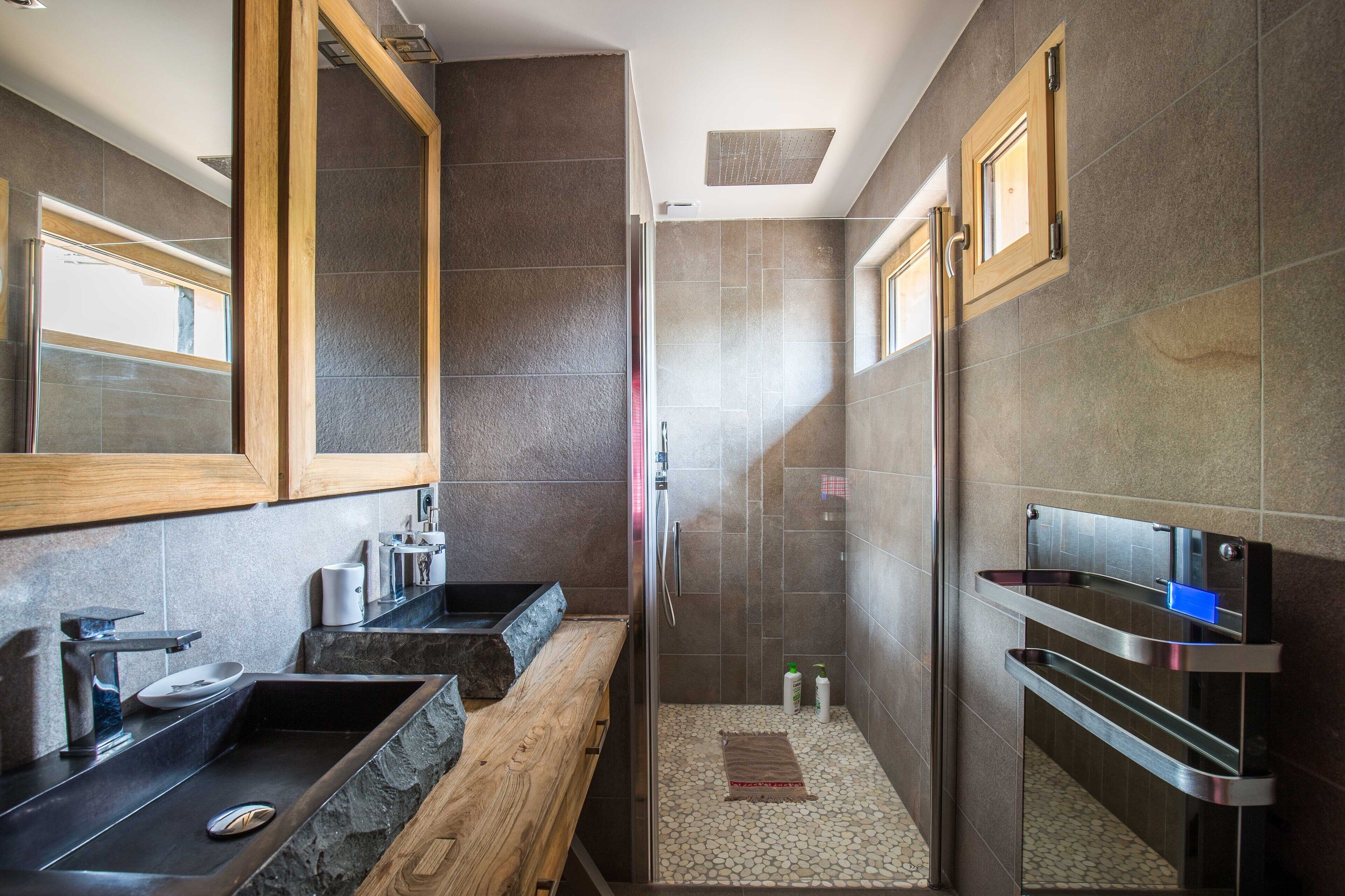 Une salle de bain moderne avec un meuble-lavabo en bois, une cabine de douche en verre et un porte-serviettes intégré.
