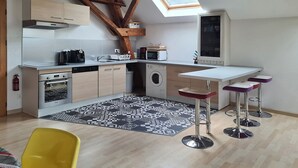 Een moderne keuken met dakraam, houten balken, een wasmachine en een bar met barkrukken.