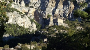 A rocky cliff with a small building at its base. - cccccccccc (Fontaine-De-Vaucluse)