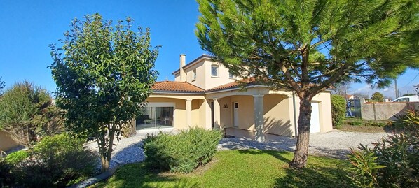 A house with a tiled roof, a covered patio, and a well-maintained garden.