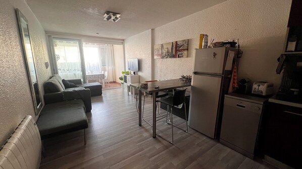 A compact living space with a kitchenette, a dining area, and a seating area with a sofa and chairs.