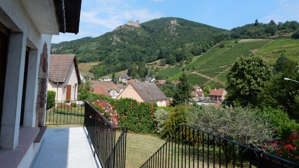 Ein Balkon mit Blick auf eine Hügel Landschaft, mit Schloss, Häusern und Weinbergen.