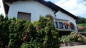 Ein weißes Gebäude mit schwarzem Dach, einem Fenster und einem Balkon mit Geländer.