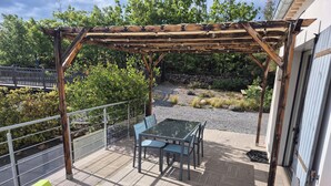 An outdoor patio with a pergola, a table with chairs, and two colorful chairs. - Little house with pool 4 people (Payzac)