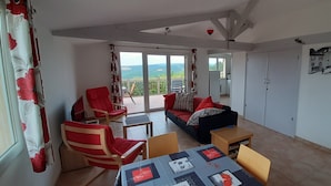 Ein Wohnzimmer mit einer Couch, Sesseln, einem Tisch und Blick ins Freie.