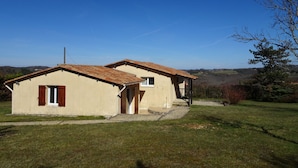 Ein zweistöckiges Haus mit geneigtem Dach, einer kleinen Veranda und einem Rasen.
