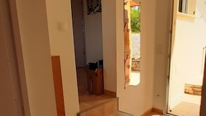Eine Treppe führt zu einem Bereich im zweiten Stock, mit einer kleinen Zwischenplattform und einer Tür nach draußen.