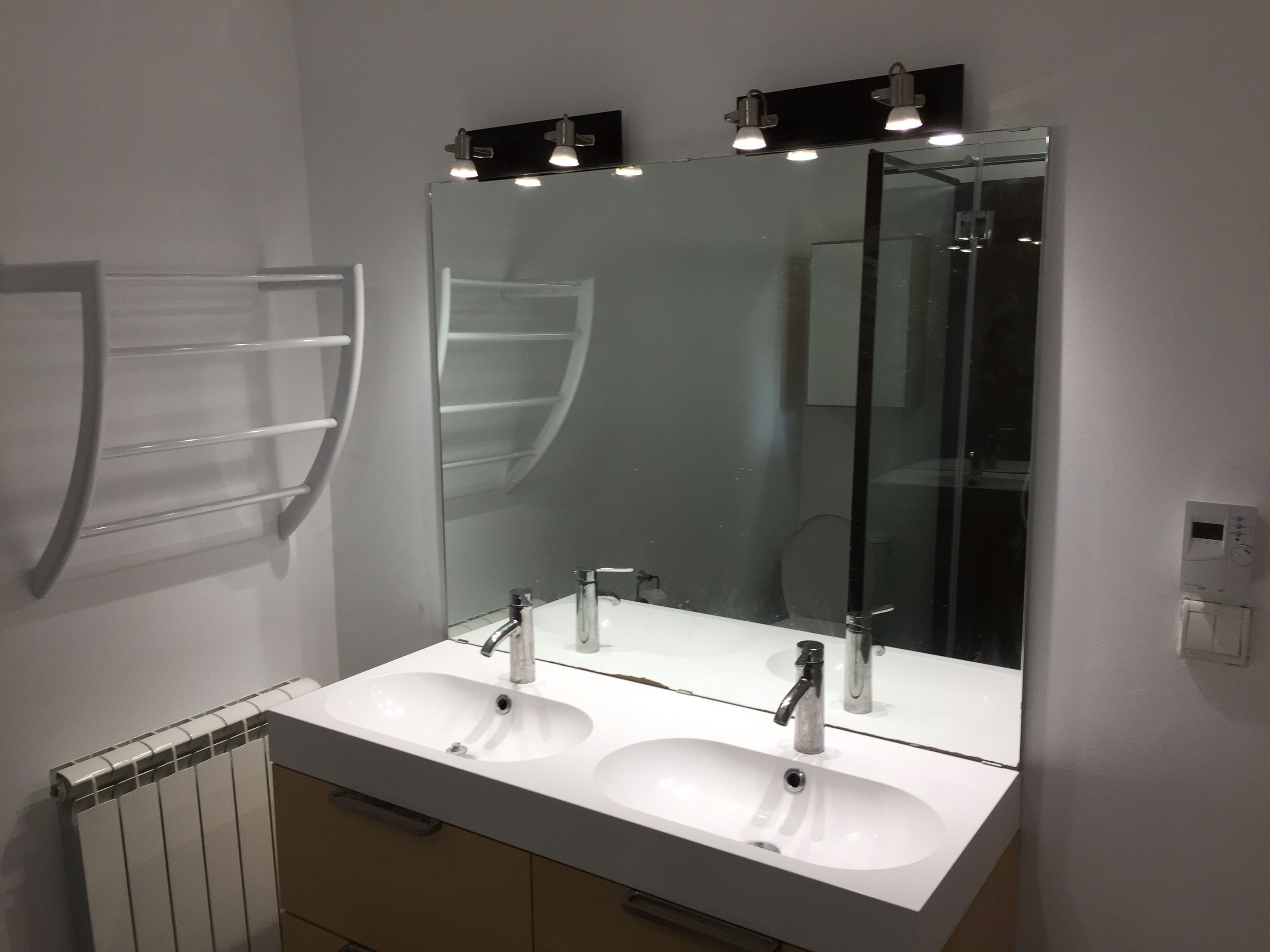 A bathroom with a double sink, a large mirror, and a towel rack.