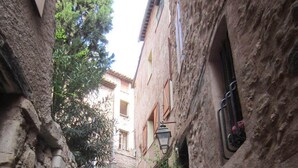 Uma escadaria de pedra estreita conduz a um edifício com arquitetura tradicional, ladeada por árvores e um muro de pedra.