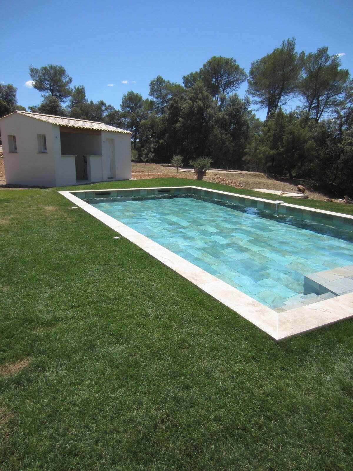 Ein rechteckiger Pool mit Fliesenrand, umgeben von gepflegtem Rasen.