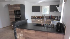 Uma cozinha moderna com ilha central, forno embutido e eletrodomésticos em aço inoxidável.