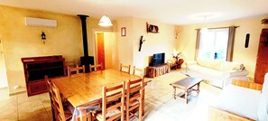 A dining area with a wooden table and chairs, a television, and a sofa.