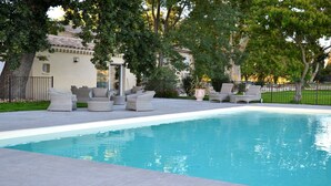 A swimming pool with lounge chairs and a building in the background. - Le 7 Mas - Suite Angélique & Adrienne (Saint-Andiol)