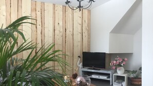 Una sala de estar moderna con una pared de acento de madera, un televisor de pantalla plana, una mesa de centro y una planta en maceta.