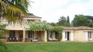 Ein zweistöckiges Haus mit Terrasse und Rasenfläche.
