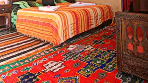 A traditional room with a bed, a wooden cabinet, and a patterned carpet. - riad atlas prestige (imlil)