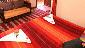 A room with a sofa, a patterned rug, and a hanging light fixture. - riad atlas prestige (imlil)