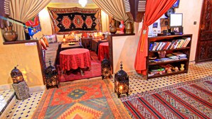 A traditional room with a patterned rug, a bookshelf, and a sign indicating no smoking. - riad atlas prestige (imlil)