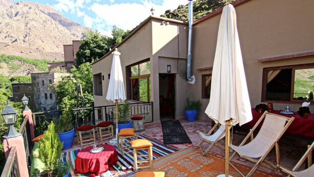 A terrace with outdoor seating, potted plants, and a view of a mountain. - riad atlas prestige (imlil)