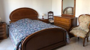 A bedroom with a wooden bed, a dresser, a chair, and a mirror.