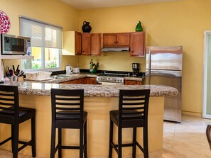 A kitchen with a central island, wooden cabinets, stainless steel appliances, and a window providing natural light.