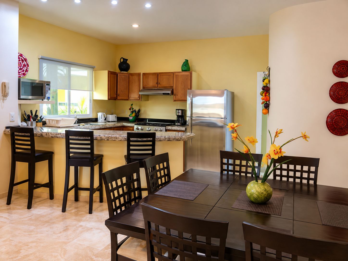 A modern kitchen with wooden cabinets, stainless steel appliances, and a dining area with a table and chairs.
