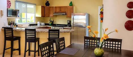 Una cocina moderna con armarios de madera, electrodomésticos de acero inoxidable y un comedor con mesa y sillas.