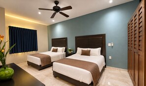 A hotel room with two beds, a ceiling fan, a nightstand, a vase with flowers, and a window with curtains.