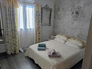 Ein Schlafzimmer mit Bett, Vorhängen, einer Wanduhr und einer Wandleuchte.