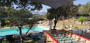 Ein Poolbereich mit Tischfußball, Liegestühlen und Blick auf die Berge.