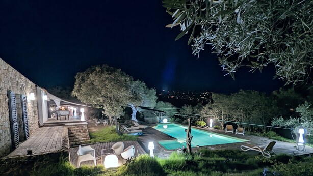 A nighttime outdoor area with a swimming pool, stone walls, and outdoor seating. - Villa in Lumio, large swimming pool, wooded park   (Lumio)