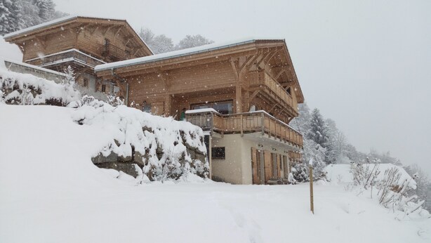 A wooden chalet with a balcony, surrounded by snow-covered trees. - Studio with a View of Mont Blanc in Sallanches (Sallanches)