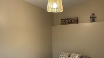 A bedroom with a bed, a chair, a hanging light fixture, and a wall sign.