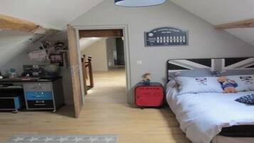 Ein Schlafzimmer mit geneigter Decke, einem Bett mit Union-Jack-Muster, einem Schminktisch, einem Schreibtisch mit einem Computer und einem kleinen roten Koffer.