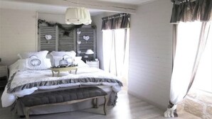 A bedroom with a bed, bedside tables, a bench, and a window with curtains.