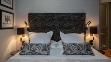 Relax in comfort with a large bed and two pillows, flanked by wall-mounted lamps.