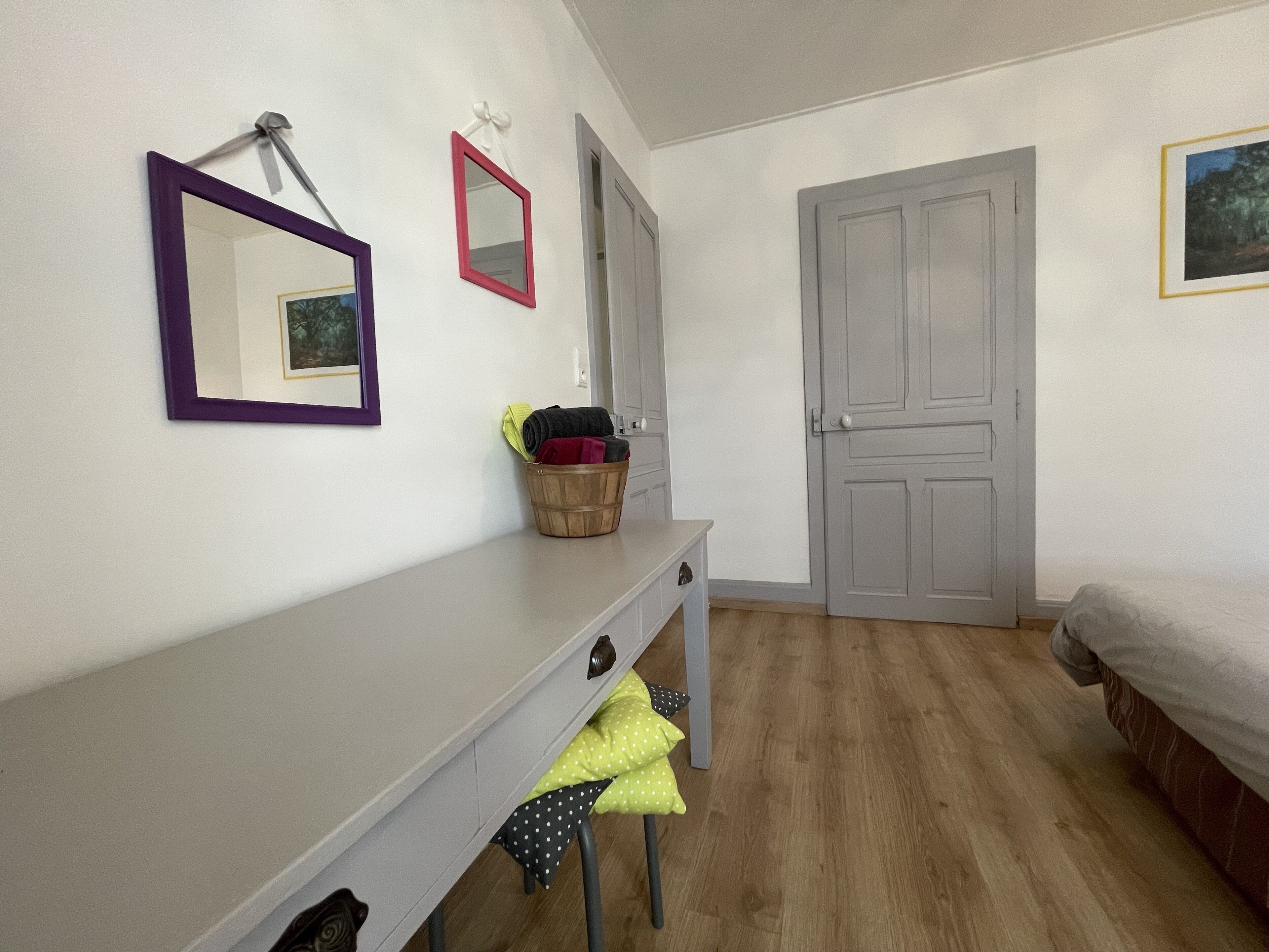 A bedroom with a bed, a dresser, a mirror, and a door.